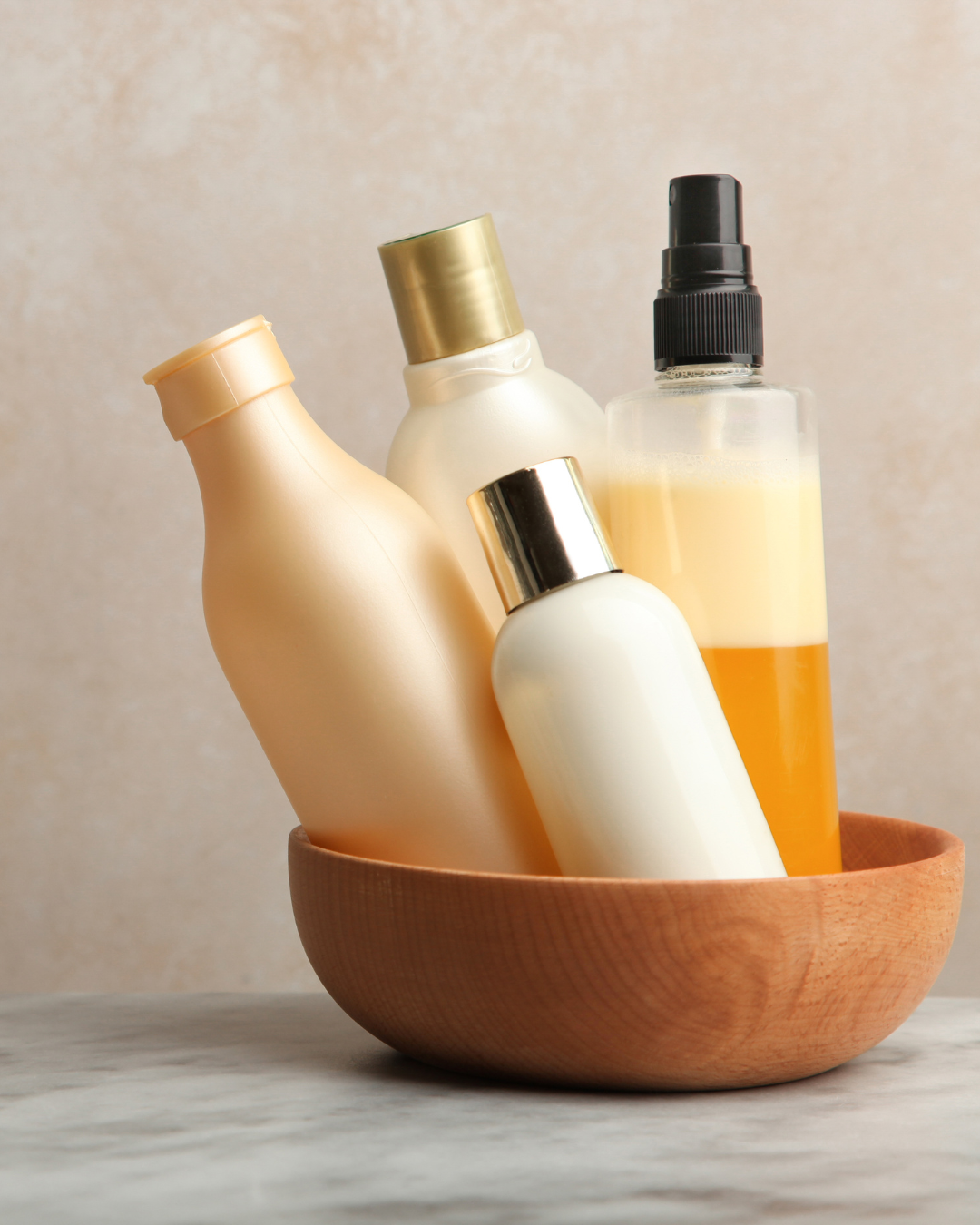 Soins capillaires naturels maison : flacons et spray contenant shampoings et après-shampoings, présentés dans un bol en bois, pour des ateliers DIY Khanalyä dédiés aux cheveux.